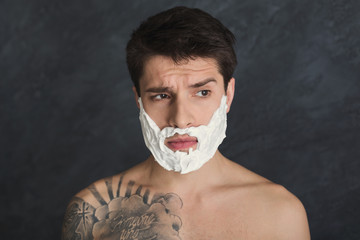 Serious tattooed man with foam on face