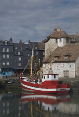  red boat on the background of houses in Normandy on a sunny afternoon in March