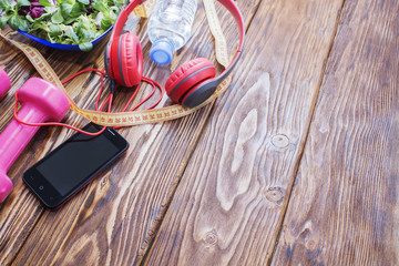 Fresh organic vegetables with dumbbells on a wooden countertop, copy space, diet, and the concept of healthy eating. Headphones and phone. Music in sports