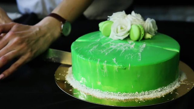 confectioner hands cut down whole reen cake in two parts