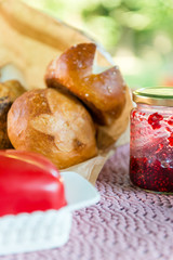 Served table for breakfast with homemade pretzel bread and red jam and butter on blurred background
