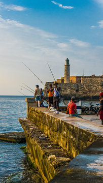 Havana, Cuba. June 2018. El Malecon of Havana: cuban people fishing and relaxing during the sunset hours of a summer cuban day at the harbour.