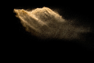 Plakat Golden sand explosion isolated on black background. Abstract sand cloud. Golden colored sand splash against dark background. Yellow sand fly wave in the air.
