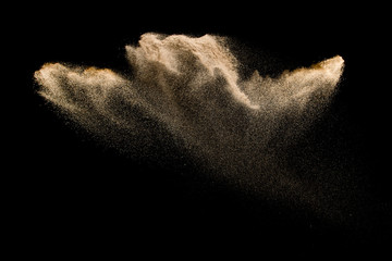 Golden sand explosion isolated on black background. Abstract sand cloud. Golden colored  sand...