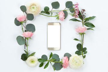 Flower arrangement on a white background with a mobile phone in a floral frame, top view and flat lay