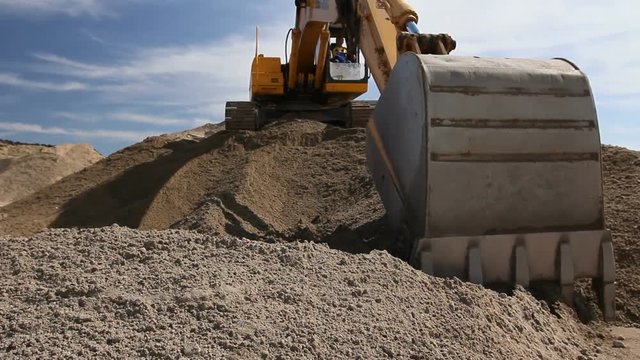Excavator is preparing pile of sand for loading in truck on building site
Yellow excavator is making pile of soil by pulling ground up on heap at construction site, project in progress.

