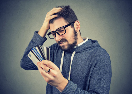 Stressed Man Looking At Too Many Credit Cards