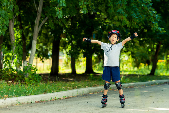 Little boy riding on rollers in the summer in the Park. Happy child in helmet learning to skate. Victory in the competition.