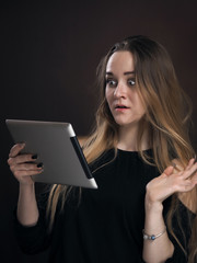 Emotional portrait of a very beautiful girl with a computer tablet in her hands.