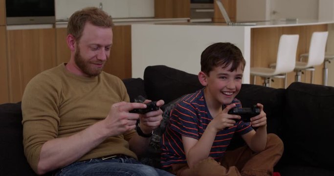 Father and son play games console in contemporary modern home, father is winning, in slow mo