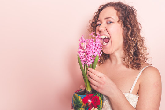 Funny curly woman bites lilac flower. Hello spring concept.