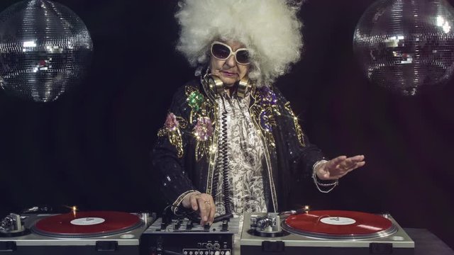 amazing DJ grandma scratching vinyl, older lady djing and partying in a disco setting. these retired rockers will get the party going.