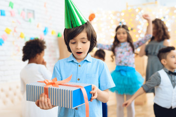 Happy birthday boy in green festive hat shows that he is happy with gift.