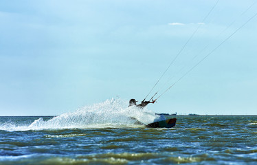Obraz premium Man riding a kite surfing on the waves in the summer.