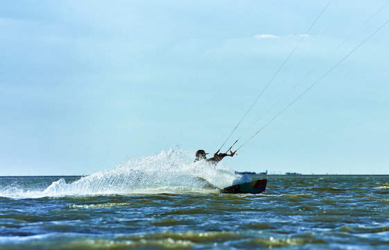 Man riding a kite surfing on the waves in the summer.