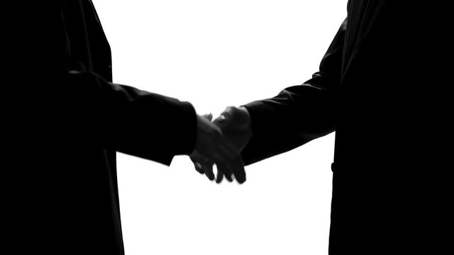 Two men handshaking after transferring suitcase, business agreement, bribe