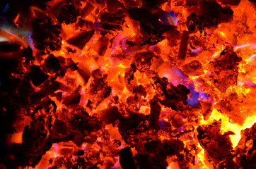 
Violet tongues of flame from burning non-ferrous metals break through the hot coal.