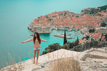 Brunette Girl tourist visiting mountain viewpoint  sightseeing in Dubrovnik, Croatia. Woman traveller in front on famous travel destination. Free brunette  enjoying vacation.
