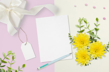 Letter, envelope and a present on pink gray background. Wedding invitation cards or love letter with chrysanthemums. Valentine's day or other holiday concept, top view, flat lay, overhead view.