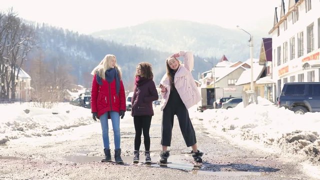 Happy women friends walking at city street in slow motion, mountains on background