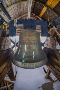 Indoor view of huge metallic bell, inside of stave Church of Lomen, during winter at Norway