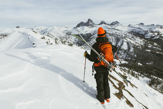 Rear view of hiker with backpack and ski standing on snowcapped mountain