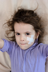 Little girl with adhesive plaster on face making selfie.