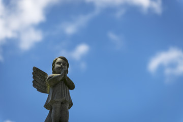 A sad angel against the blue sky in a cemetery in the city of New Orleans, Louisiana, USA