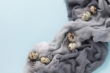 Easter decoration with quail eggs,gray fabric on blue background.