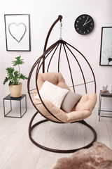 Tropical plant with green leaves and swing chair in room interior