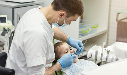 Dentist examining little boy's teeth in clinic. Dental problem.