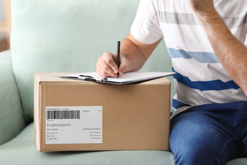 Young man preparing parcel for shipment to client at home