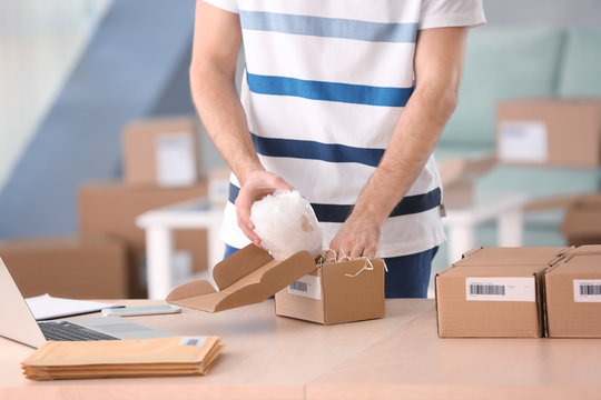 Young man preparing parcel for shipment to client at home