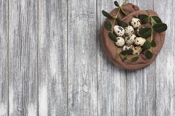 Fototapeta na wymiar Easter decoration quail eggs with brown fabric on gray wooden background.