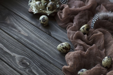 Easter decoration feathers quail eggs, brown fabric gray wooden background.