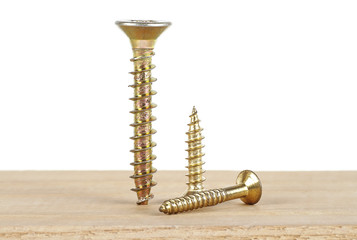 Golden screws on wooden plank, white background