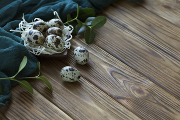 Easter decoration feathers quail eggs, green fabric on wooden brown background.
