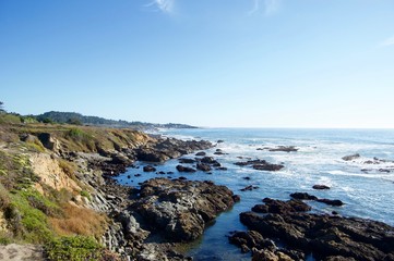 Fototapeta na wymiar Beautiful scenic coastal view in California (USA): Untouched nature of the pacific ocean with limestone rock cliffs and crashing waves with a clear blue summer sky create the perfect picturesque place