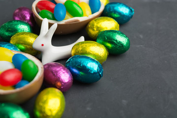 Fototapeta na wymiar Easter hare with colorful candy and chocolate eggs on grey background