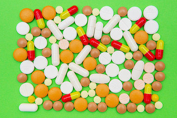 drugs capsules and pills on green background