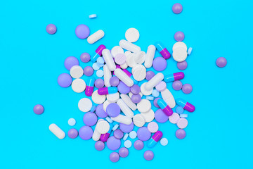 drugs capsules and pills on blue background.