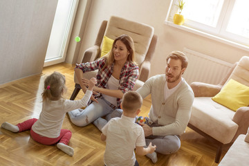 Parents with children playing together and having fun in living room