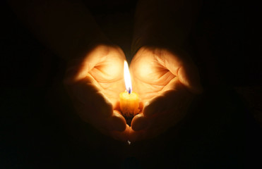 Cupped hands with burning candle.