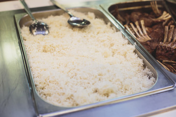 Beautifully decorated catering banquet table with different main course hot food dishes and garnish, with rice, chicken, lamb, vegetables and kebab on corporate party event or wedding celebration