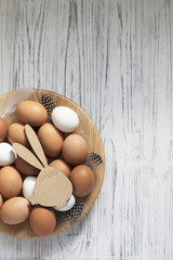 Easter eggs with feathers on wooden plate.