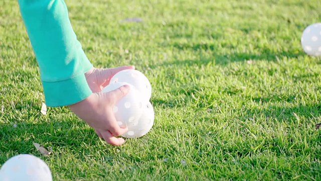 HD slow motion. White Plastic Baseballs. Poly Molded Baseball. Girl Pick Up From Grass Wiffle Balls. Sport Practice or Play in park. Softball, T-ball. Athletic Baseball Equipment. Close up. Outdoor.