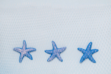 Three blue starfishes with fishing net on pastel background minimalistic concept.