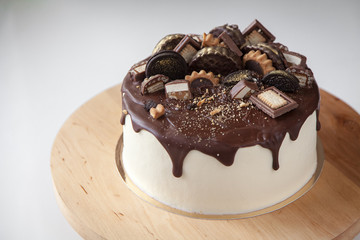 Beautiful festive cake on a wooden stand, sprinkled with gilding.