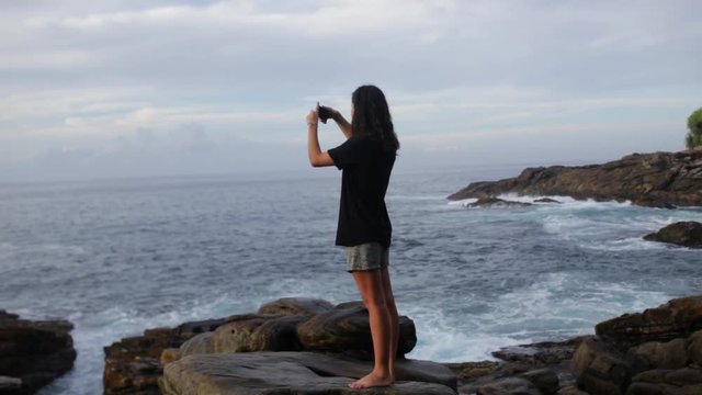 Girl takes the photo of the ocean.
