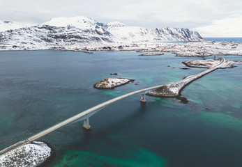 Aerial winter view of Lofoten Islands, Nordland, Norway, with fjord, road, bridge and mountains, shot from drone